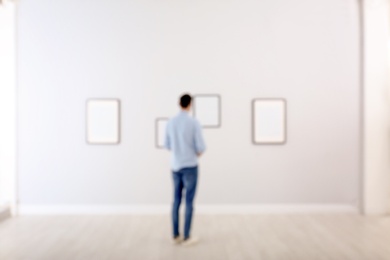 Young man in hall of modern art gallery, blurred view