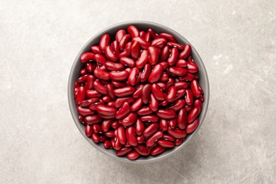 Photo of Raw red kidney beans in bowl on light grey table, top view