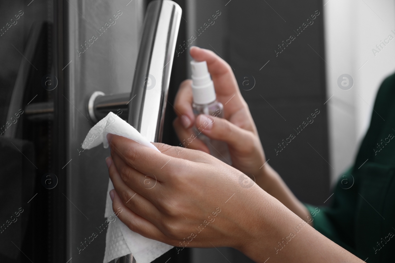 Photo of Woman cleaning door handle with wet wipe and antiseptic outdoors, closeup