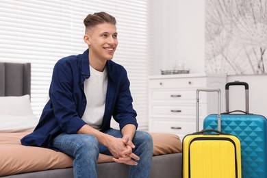 Smiling guest relaxing on bed in stylish hotel room