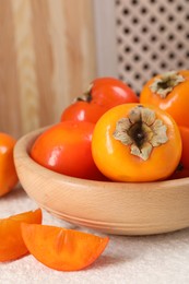 Photo of Delicious ripe persimmons on light textured table indoors