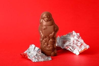 Photo of Unwrapped chocolate Santa Claus on red background
