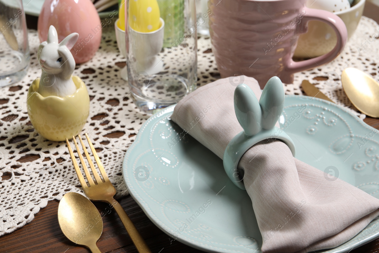 Photo of Festive table setting with napkin ring in shape of bunny ears, closeup. Easter celebration