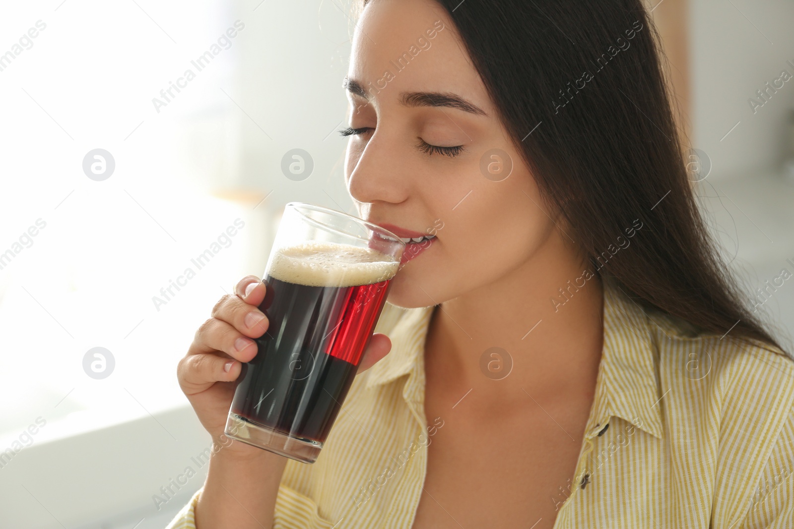 Photo of Beautiful woman with cold kvass indoors. Traditional Russian summer drink