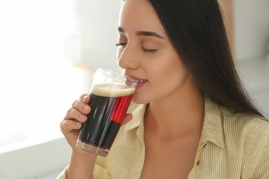 Photo of Beautiful woman with cold kvass indoors. Traditional Russian summer drink