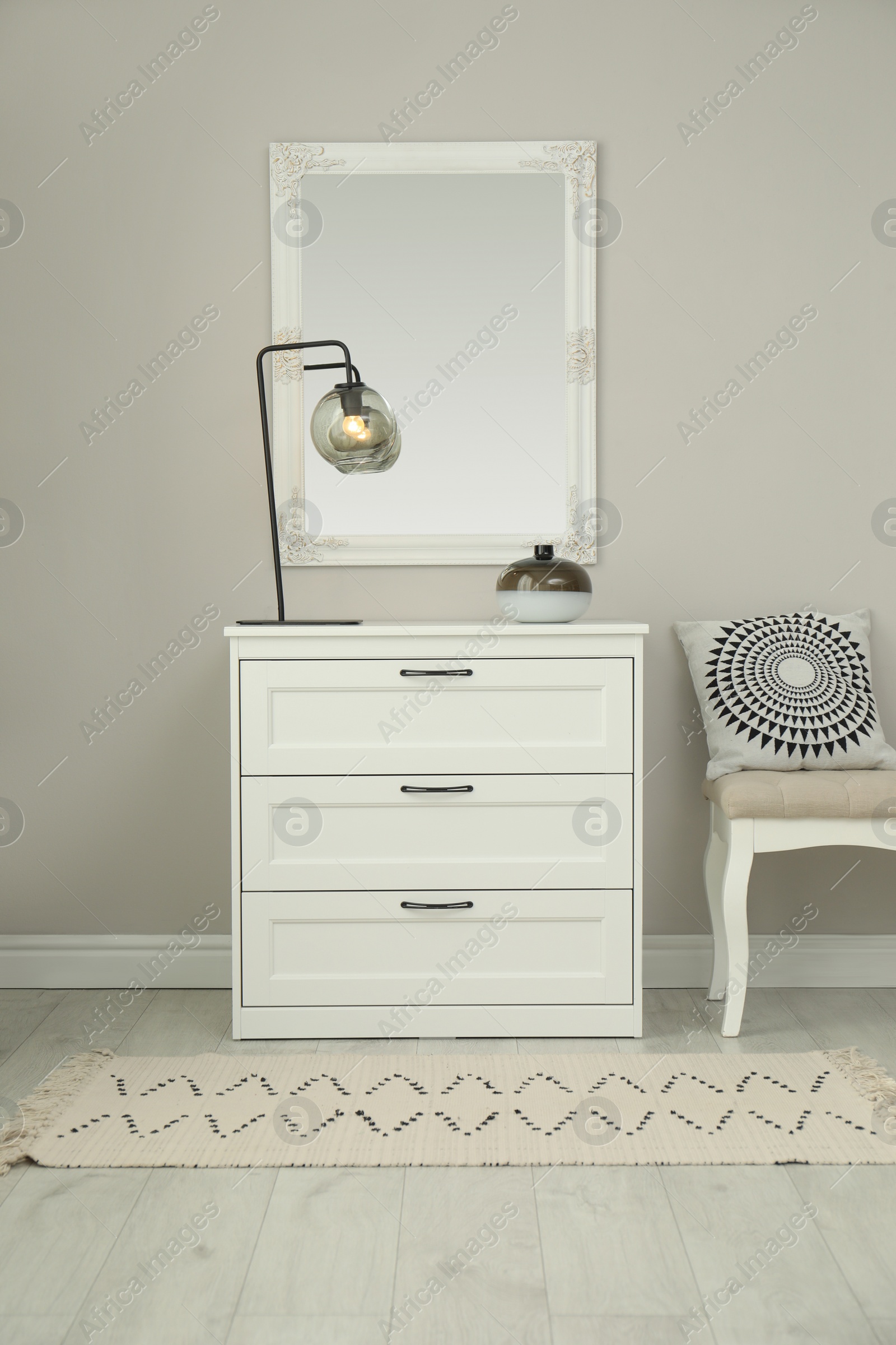 Photo of Hallway with stylish chest of drawers and mirror. Interior design