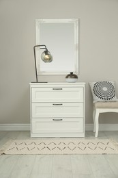 Hallway with stylish chest of drawers and mirror. Interior design