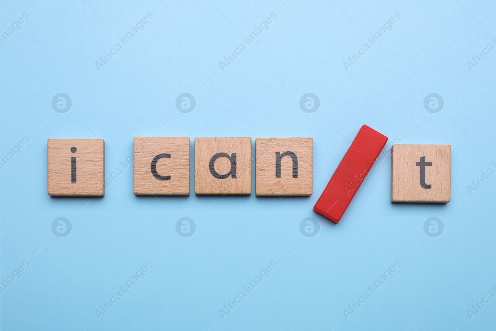 Photo of Motivation concept. Changing phrase from I Can't into I Can by adding slash symbol on light blue background, flat lay