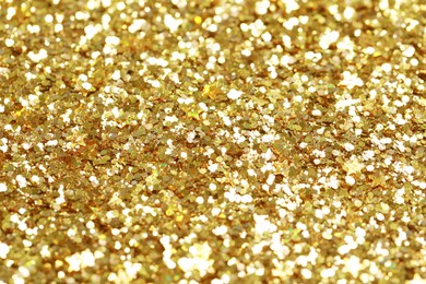 Photo of Beautiful golden shiny glitter as background, closeup