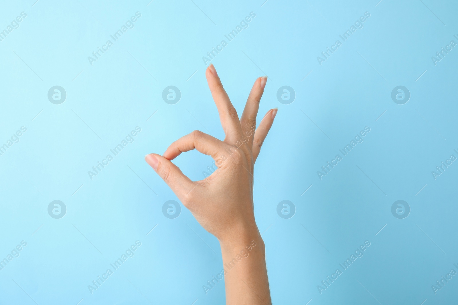 Photo of Woman showing sign okay on color background, closeup. Body language