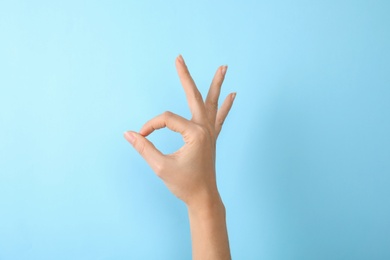 Photo of Woman showing sign okay on color background, closeup. Body language