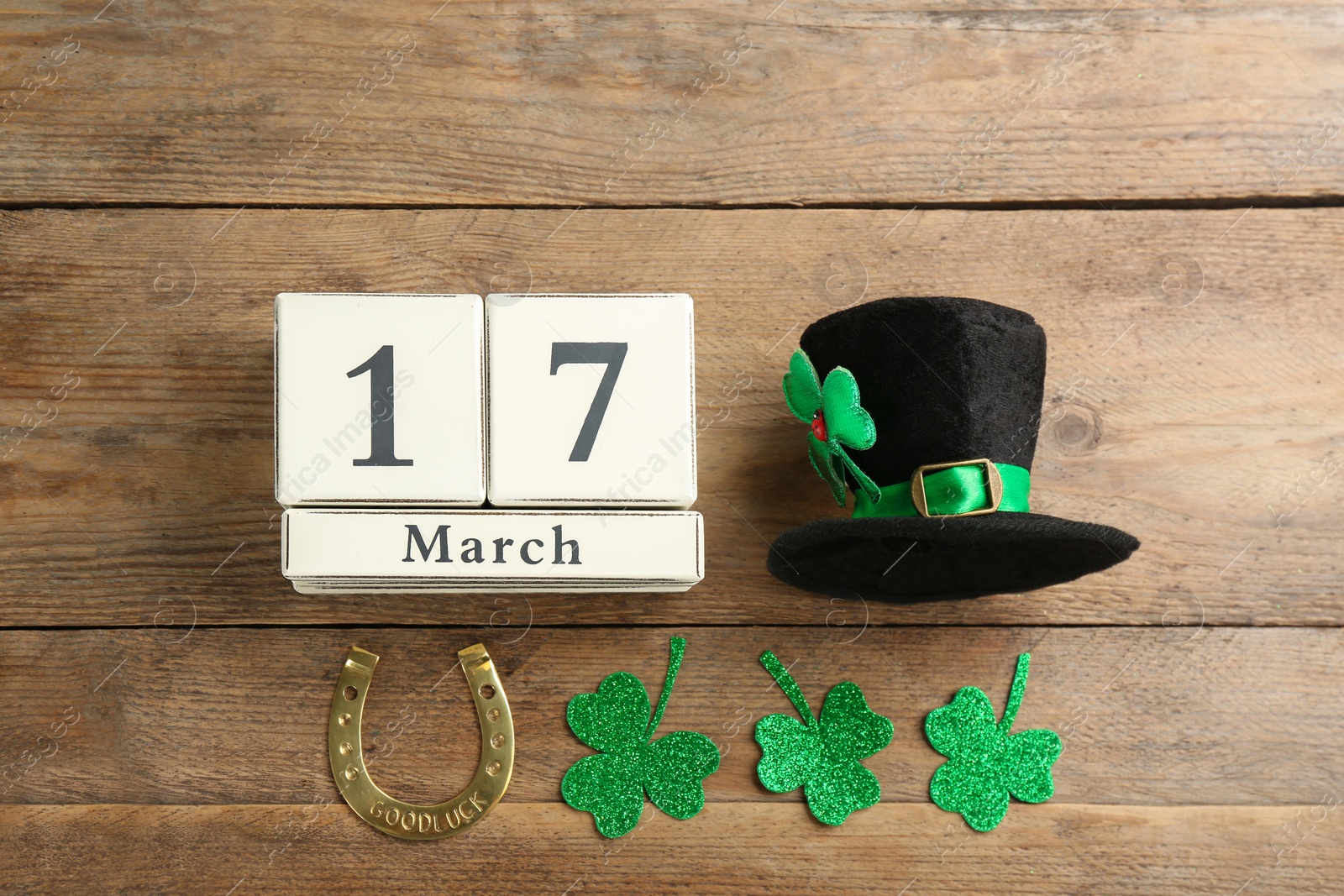 Photo of Leprechaun's hat, block calendar and St. Patrick's day decor on wooden background, flat lay