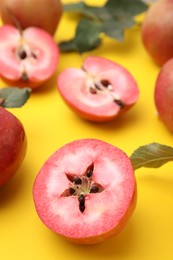 Tasty apples with red pulp and leaves on yellow background, closeup