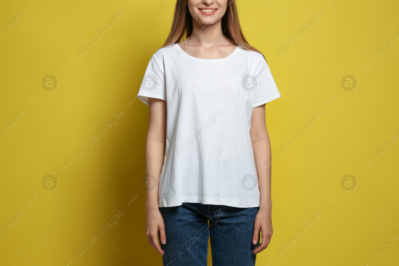 Photo of Young woman wearing blank t-shirt on yellow background, closeup. Mockup for design