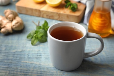 Photo of Cup of hot tea as natural cough remedy on wooden table