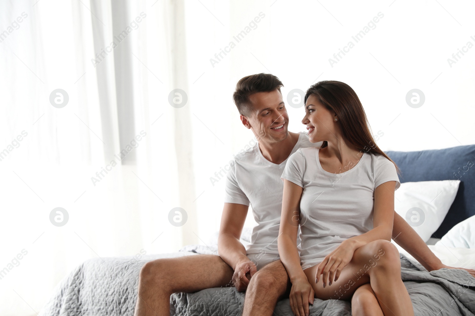 Photo of Happy couple wearing underwear in modern bedroom