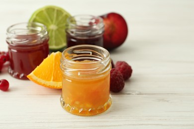 Photo of Jars of different jams and ingredients on white wooden table
