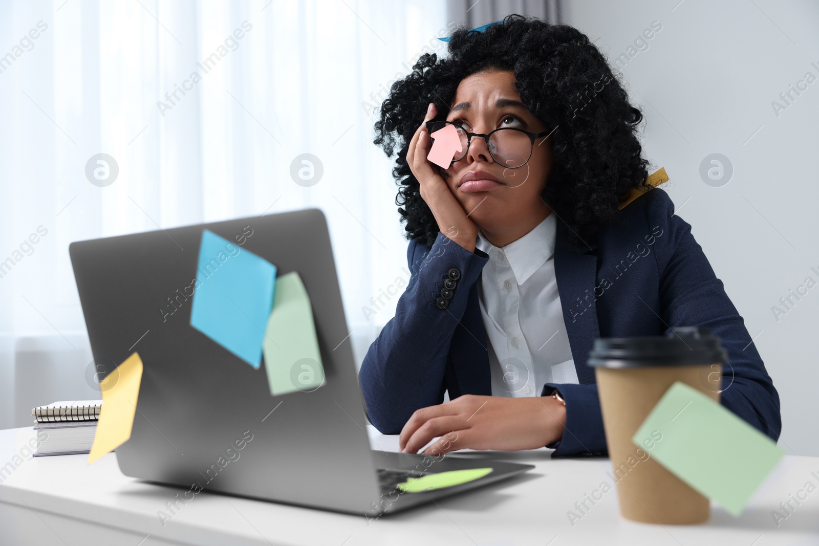 Photo of Deadline concept. Stressed woman sitting near laptop in office. Many sticky notes everywhere as reminders