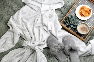 Flat lay composition with fluffy slippers and bath robe on fuzzy carpet. Comfortable home outfit