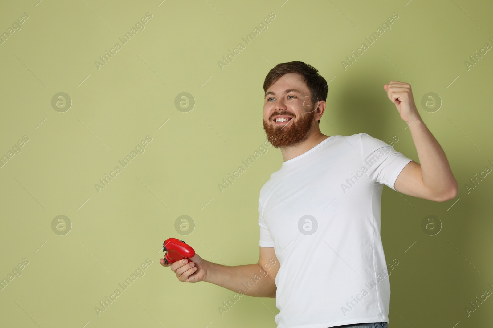 Photo of Happy man with game controller on pale green background. Space for text