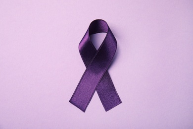 Purple ribbon on pink background, top view. Domestic violence awareness