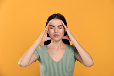 Photo of Woman suffering from migraine on yellow background