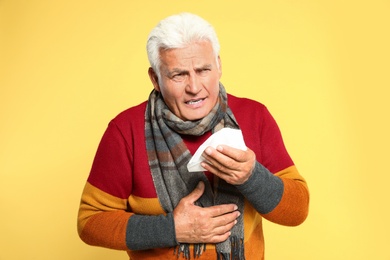 Image of Senior man coughing on yellow background. Cold symptoms
