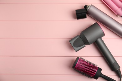 Photo of Flat lay composition with hairdressing equipment on pink wooden background, space for text