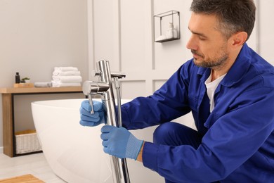 Professional plumber installing water tap in bathroom