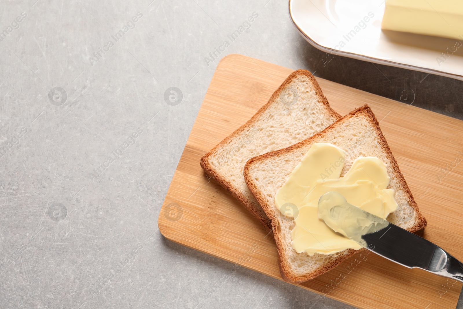 Photo of Tasty toast with butter and knife on table, top view. Space for text