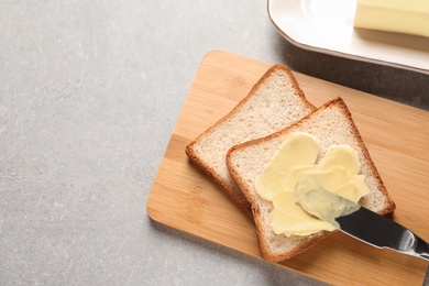 Photo of Tasty toast with butter and knife on table, top view. Space for text