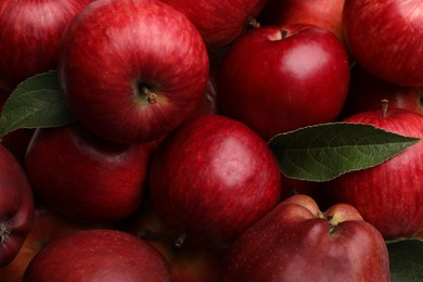 Photo of Fresh red apples and leaves as background, top view