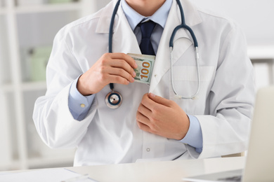 Photo of Doctor putting bribe into pocket in clinic, closeup. Corrupted medicine