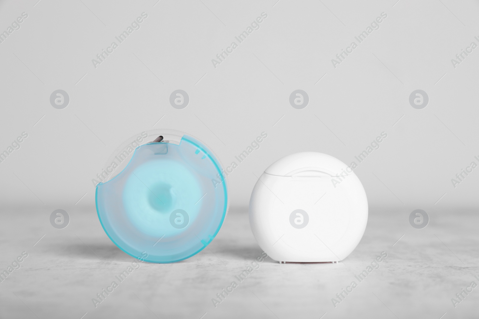 Photo of Containers with dental floss on light grey textured table