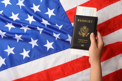 Woman holding passport with ticket over flag of USA, closeup