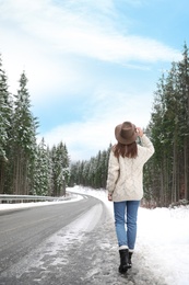 Young woman walking near snowy forest. Winter vacation