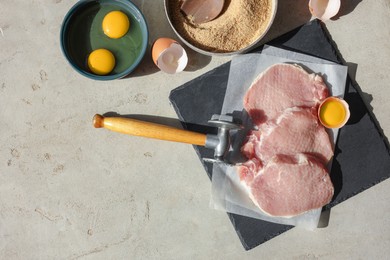 Photo of Cooking schnitzel. Raw pork chops, meat mallet and ingredients on grey table, flat lay with space for text