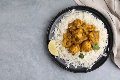 Photo of Delicious chicken curry with rice on grey table, top view. Space for text