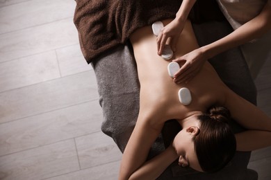 Photo of Spa therapy. Beautiful young woman lying on table during hot stone massage in salon, top view. Space for text
