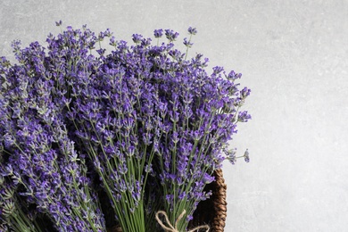 Fresh lavender flowers in basket on grey stone table, top view. Space for text