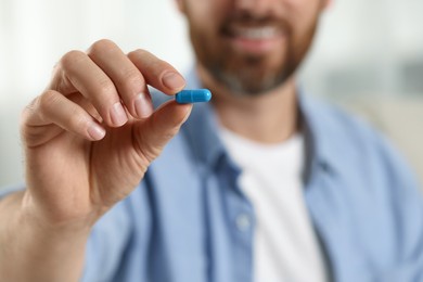 Photo of Man with pill on blurred background, closeup view