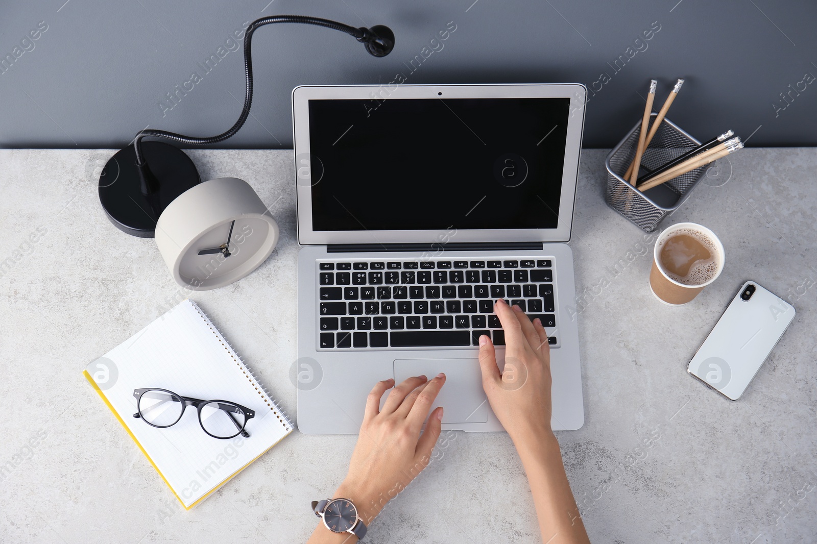 Photo of Female blogger using laptop at table, top view. Blank screen for mockup