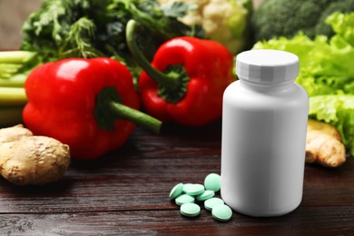 Photo of Dietary supplements. Plastic bottle, pills and food products on wooden table