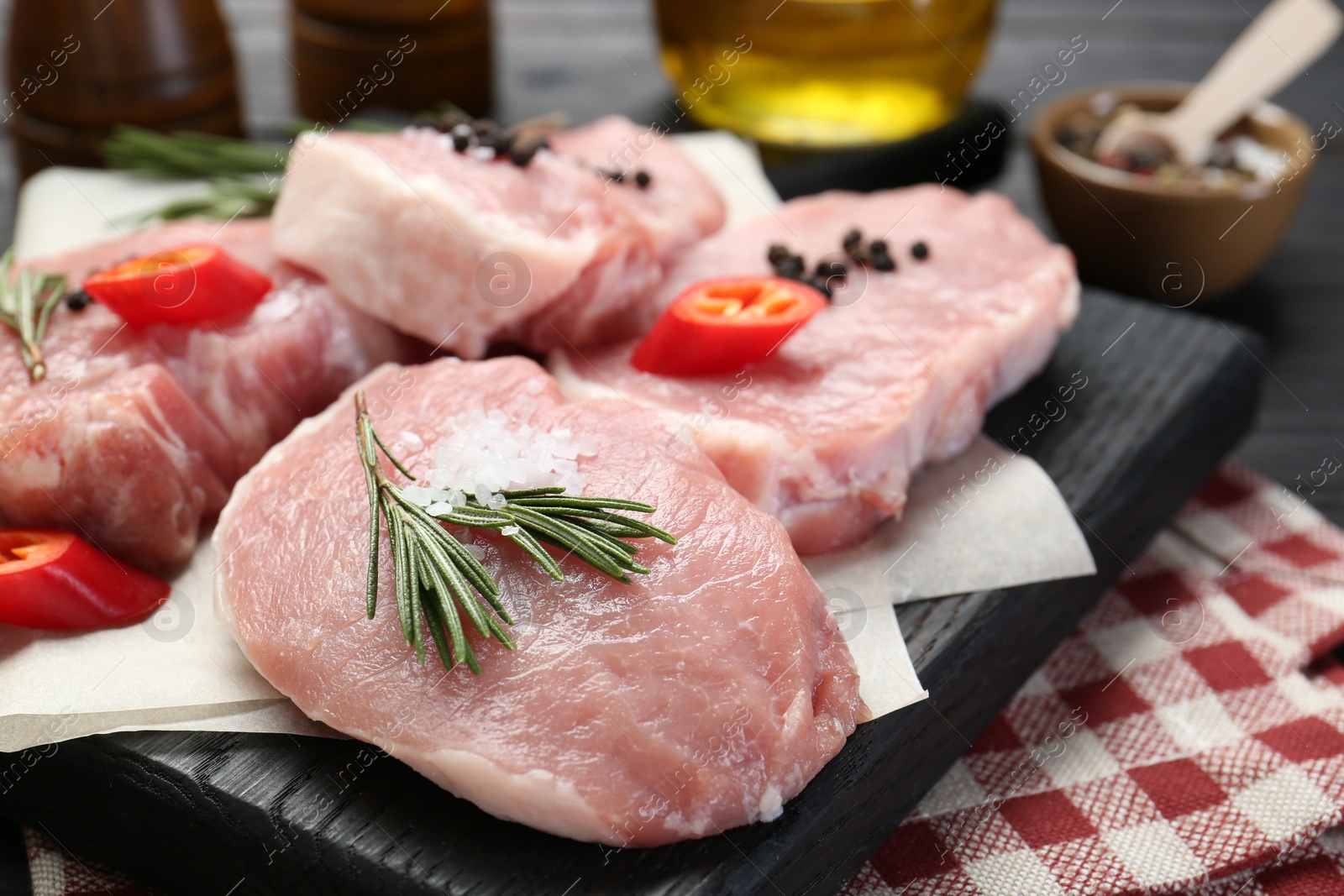 Photo of Pieces of raw pork meat with chili pepper and spices on table, closeup