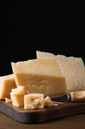 Photo of Delicious parmesan cheese with knife on wooden table