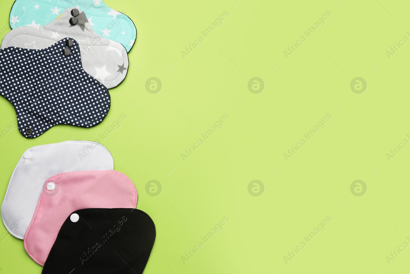 Photo of Many reusable cloth menstrual pads on green background, flat lay. Space for text