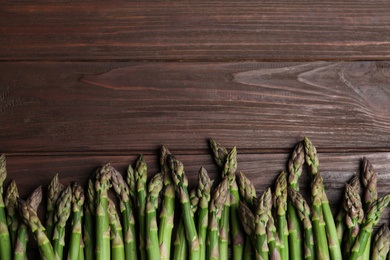 Fresh raw asparagus on wooden table, flat lay. Space for text