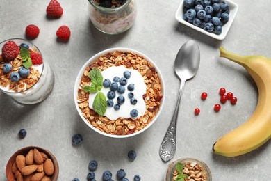 Photo of Flat lay composition with delicious yogurt, granola and berries on grey table, flat lay