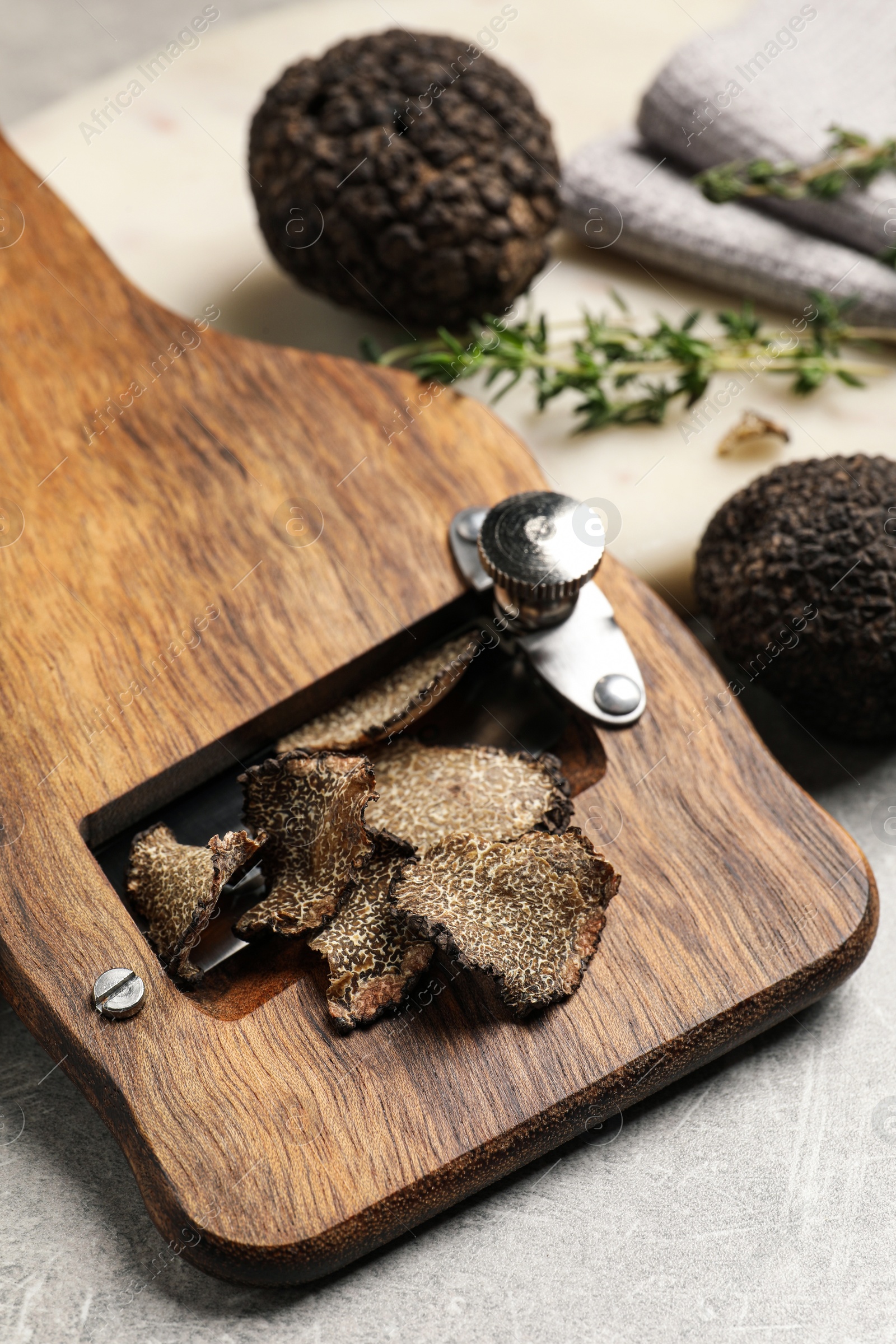 Photo of Fresh black truffles and slicer on grey table, closeup