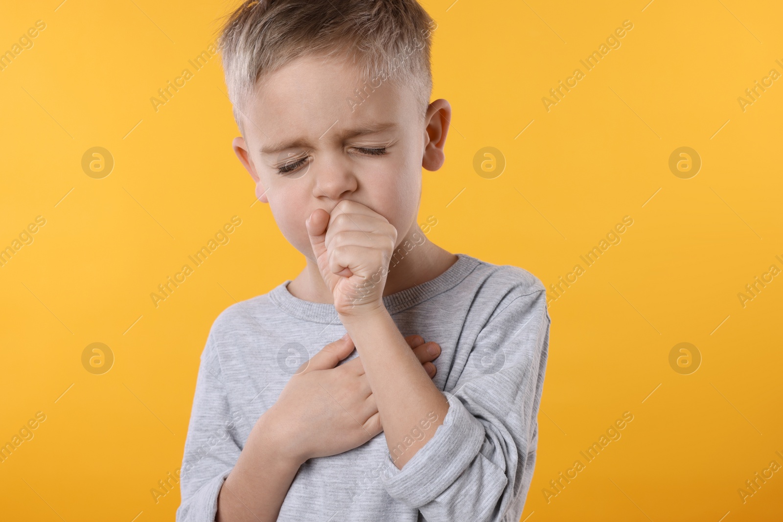 Photo of Sick boy coughing on yellow background. Cold symptoms